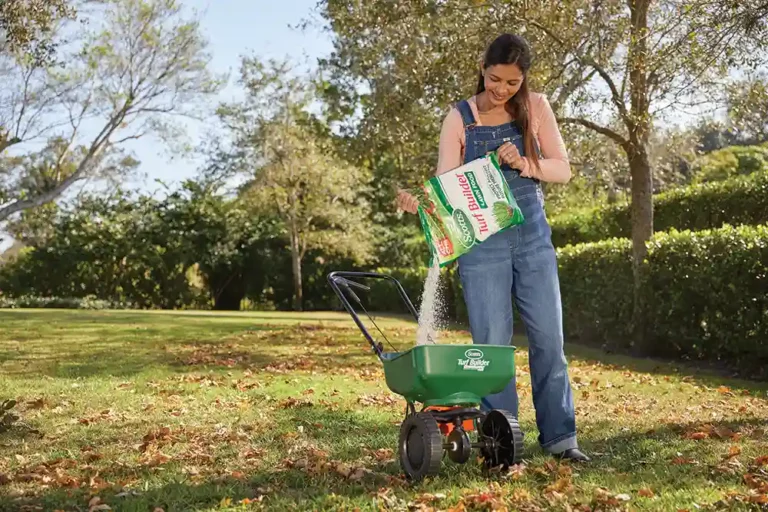Woman pouring Scott's Turf Builder into seed spreader